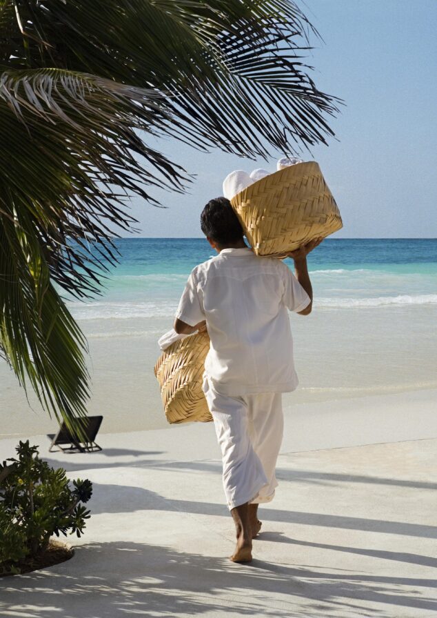 Beach hotel staff walking to beach with palms surrounding