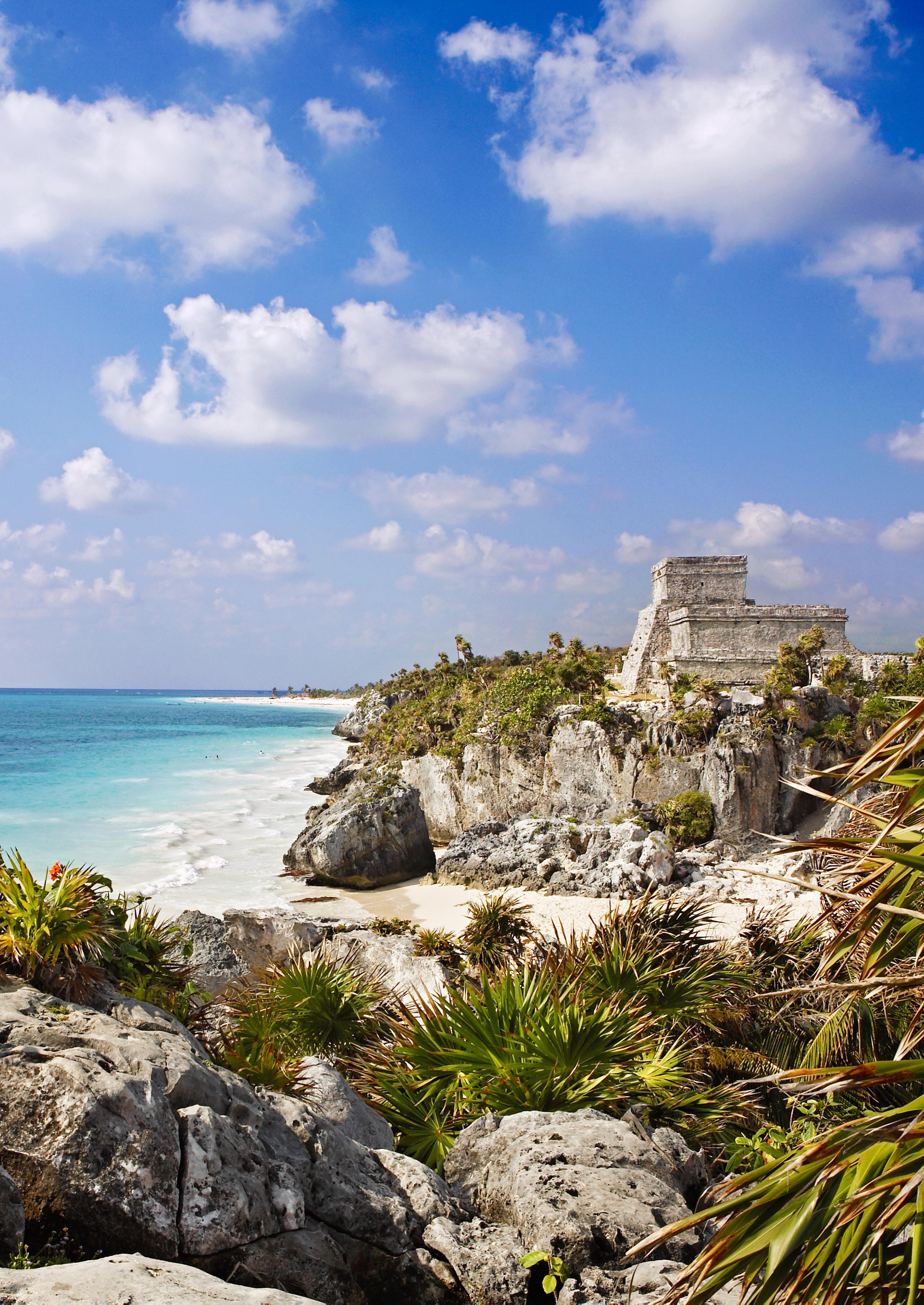 rocky beach shore in tulum with blue water in distance
