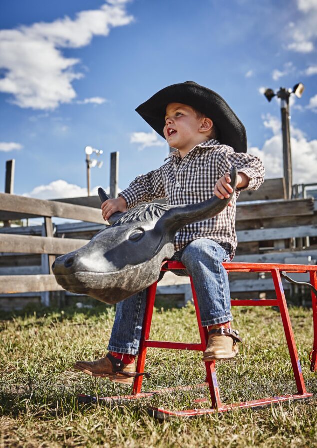 child wearing cowboy hat riding toy bull ride
