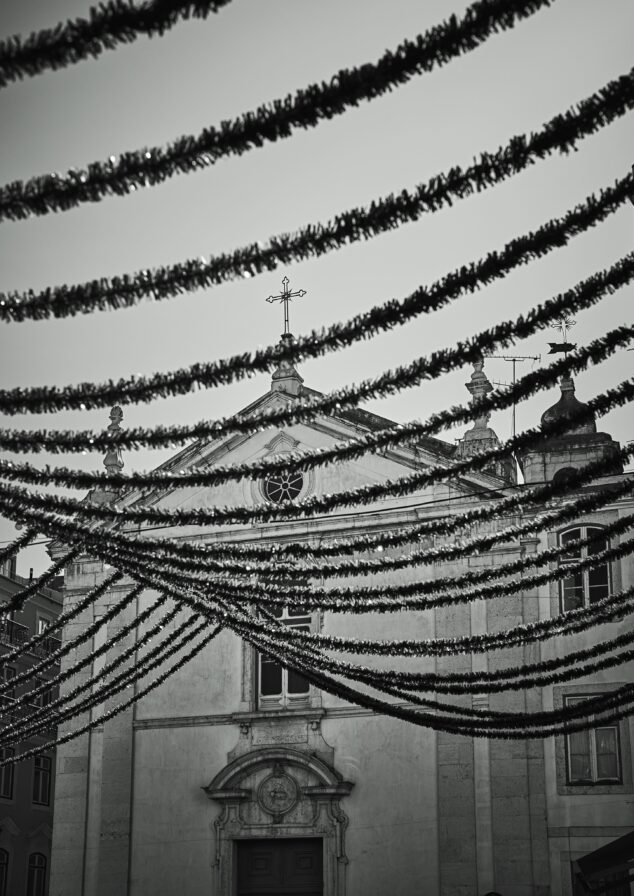 Black and white photo of a church façade with strands of decorative garlands hanging above.