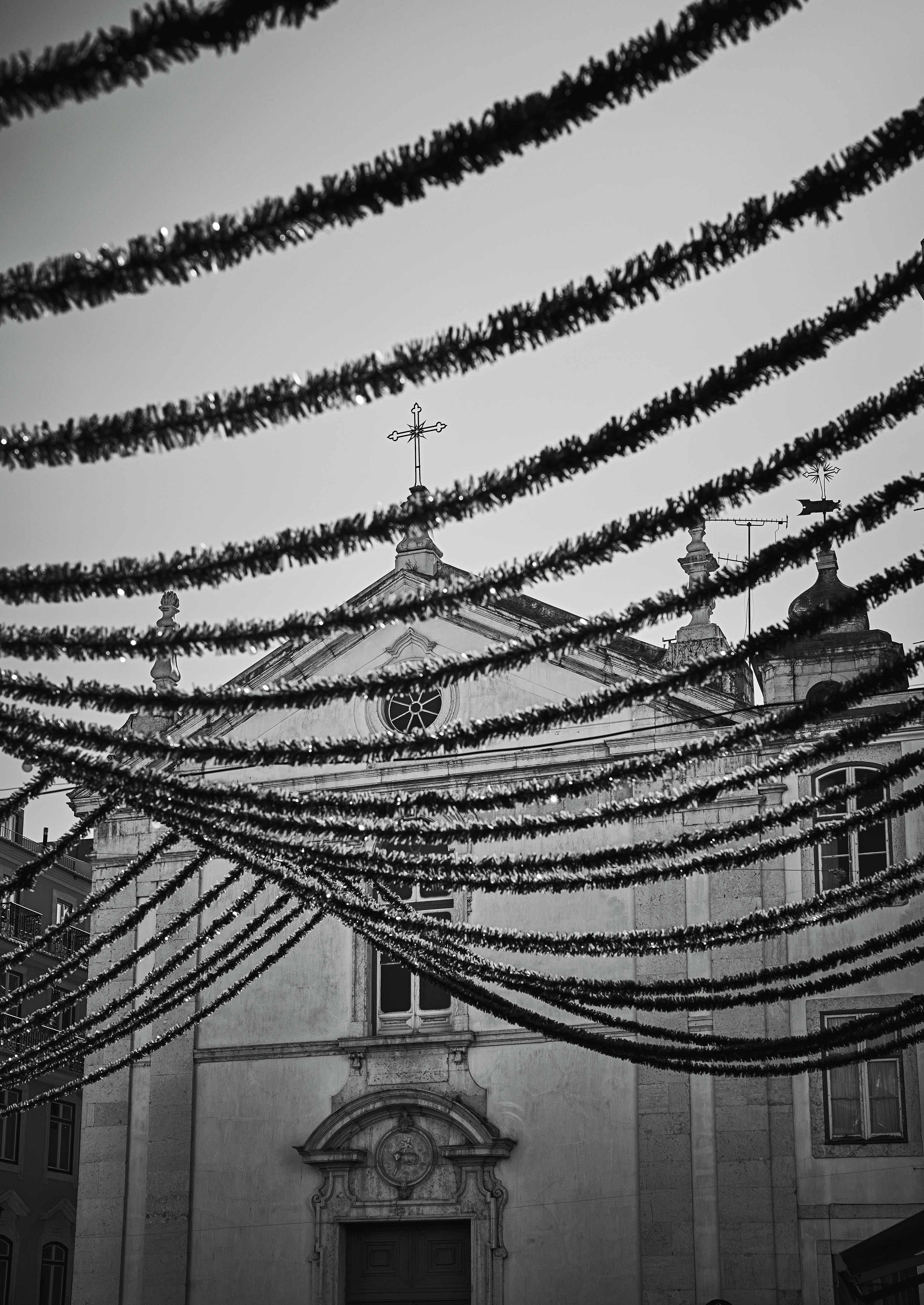 Black and white photo of a church façade with strands of decorative garlands hanging above.