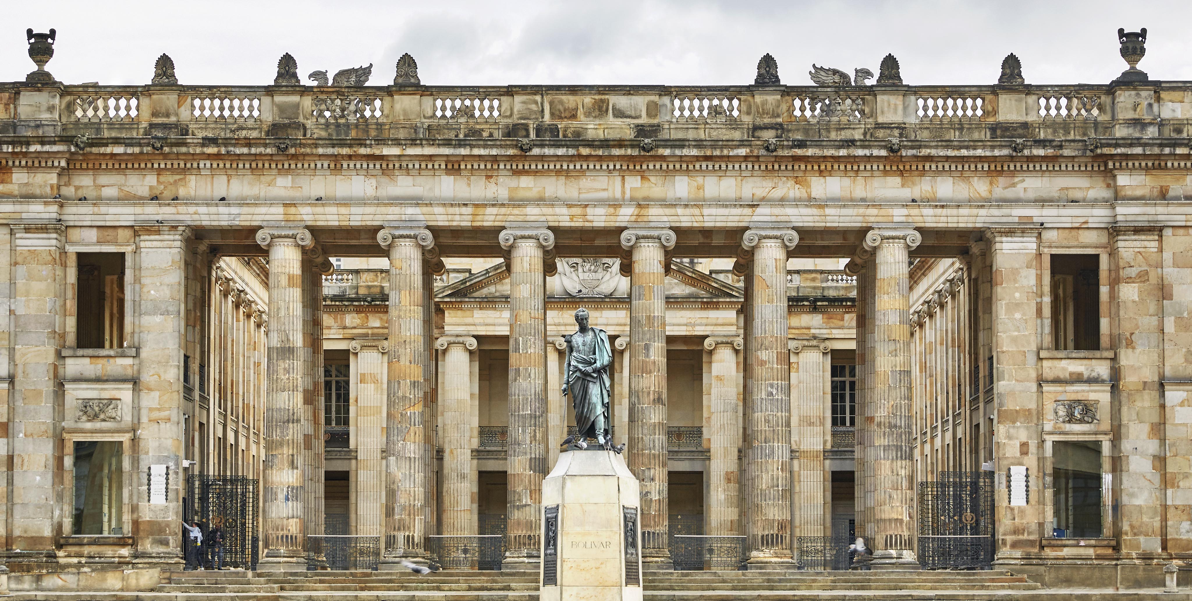 Stone building with tall columns and a statue in front, under a cloudy sky, reminiscent of historic South America. Plaque reads "Nariño.”.