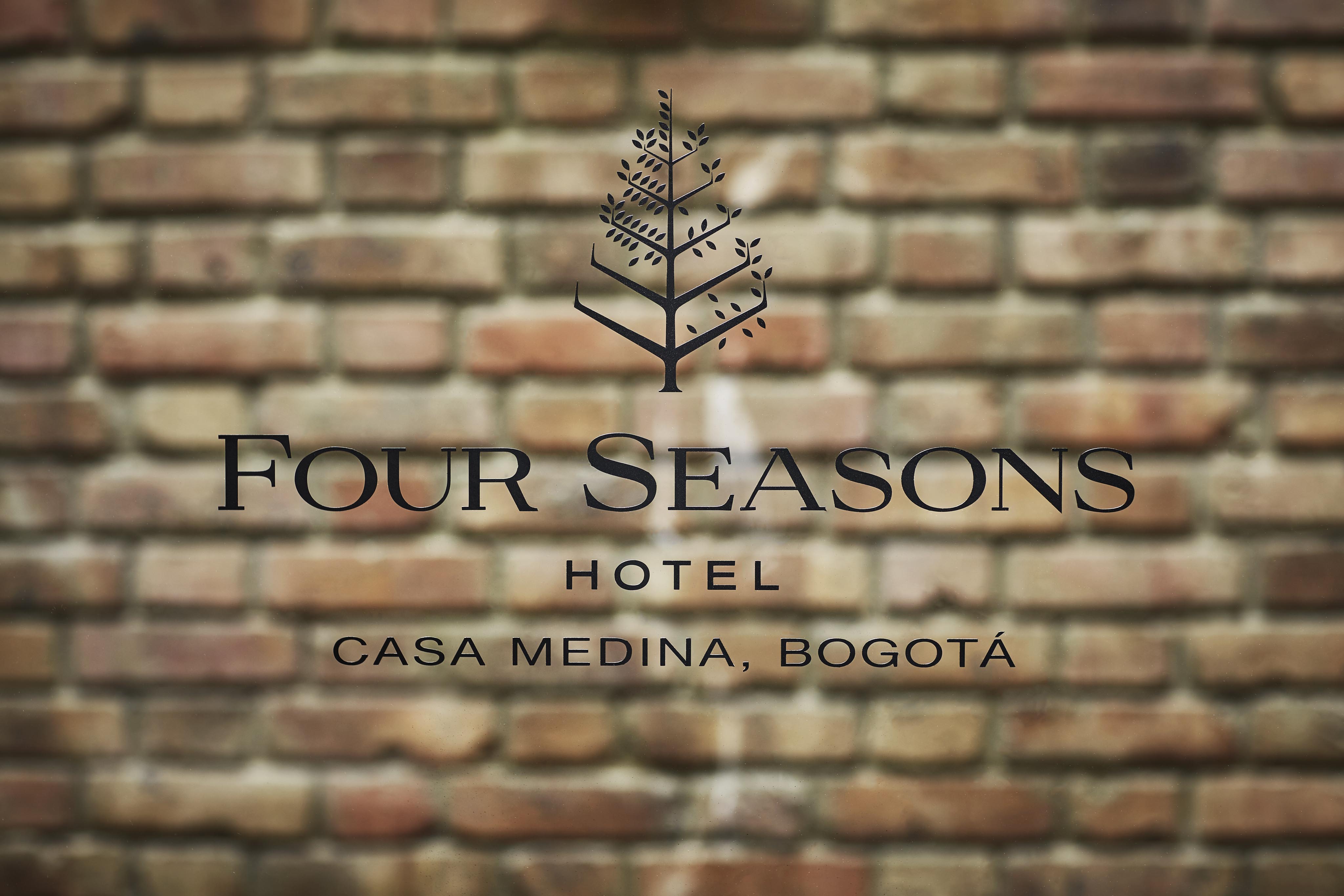 A sign on a brick wall reads "Four Seasons Hotel Casa Medina, Bogotá," with a decorative tree logo above the text, elegantly capturing the charm of South America.