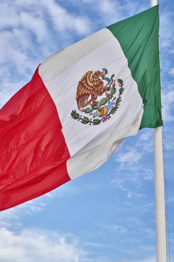 Mexican flag waving in wind with blue skies behind