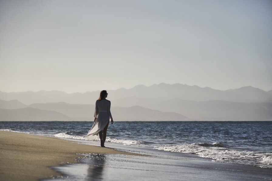 woman walking on shoreline of serene Baja beach