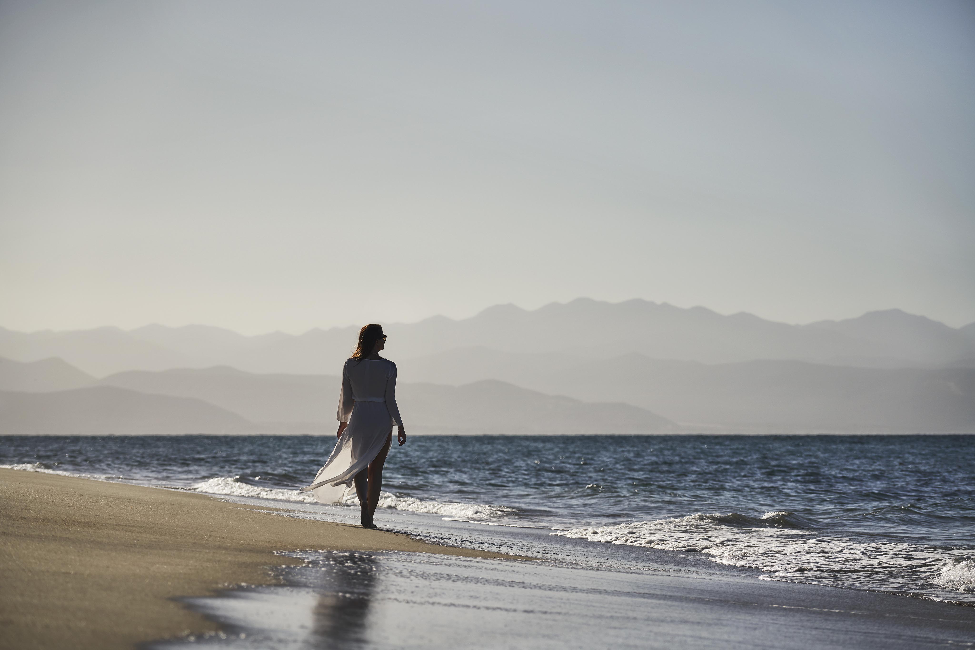woman walking on shoreline of serene Baja beach
