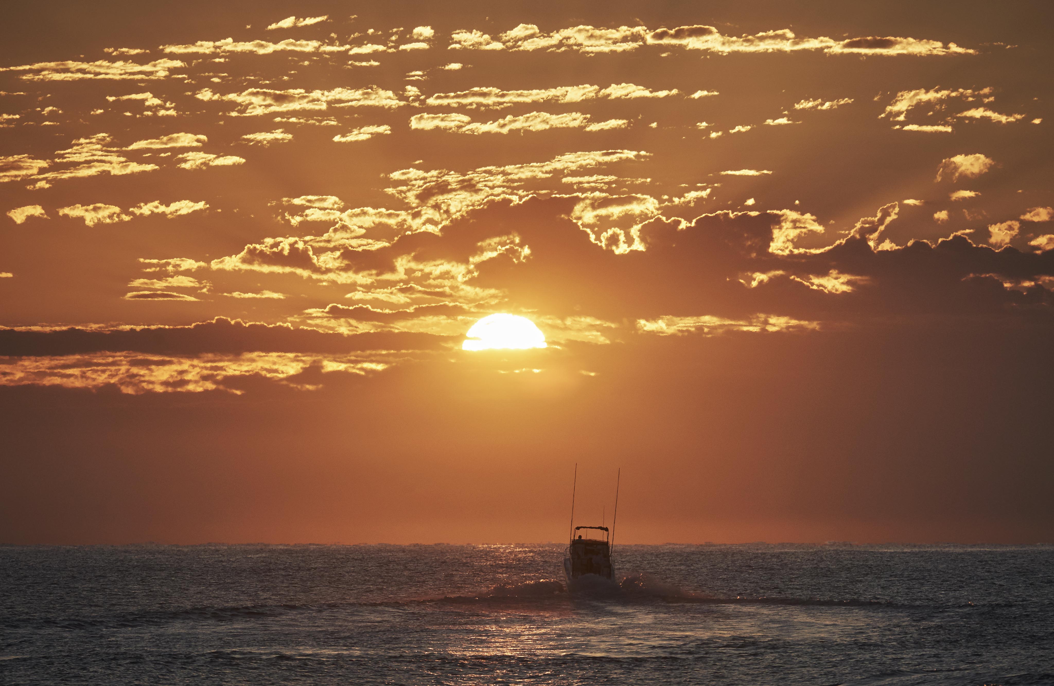 Fishing boat rushing towards the Baja Los Cabos ocean horizon at sunset