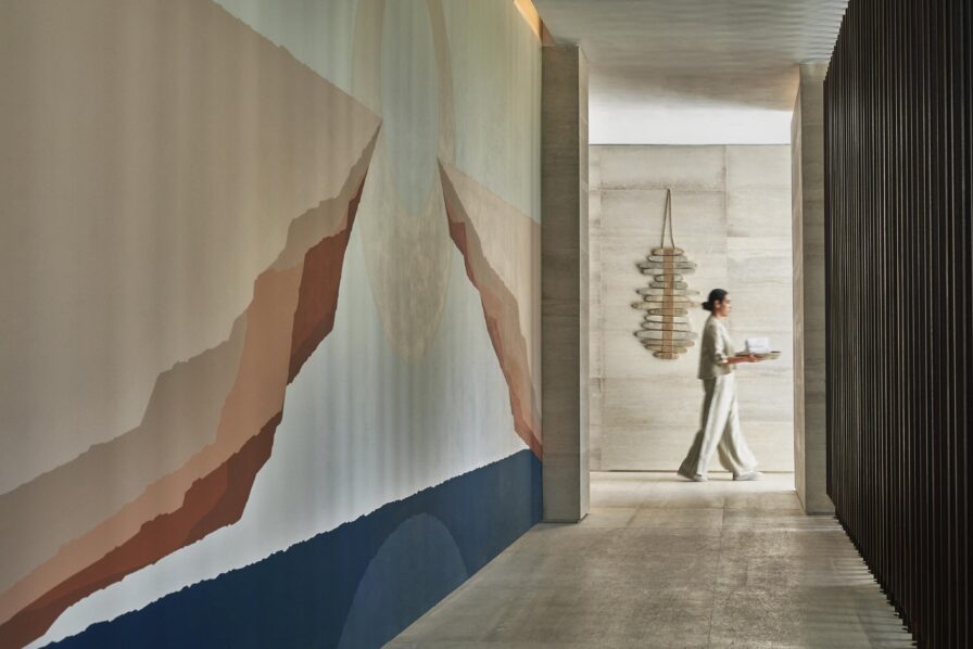 Luxury Los Cabos Spa hospitality staff service in open air corridor with mural within Four Seasons Los Cabos interior.