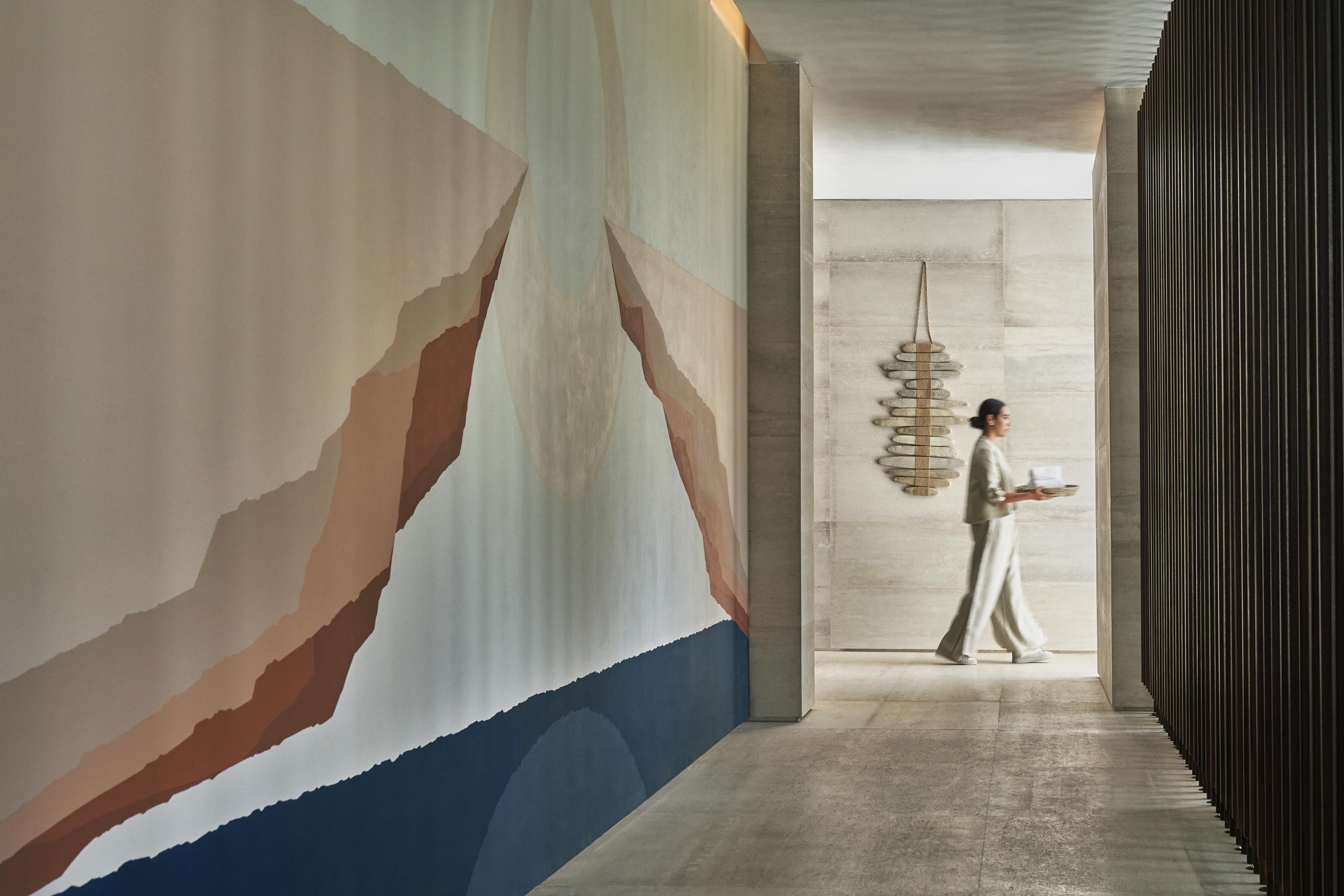 Luxury Los Cabos Spa hospitality staff service in open air corridor with mural within Four Seasons Los Cabos interior.