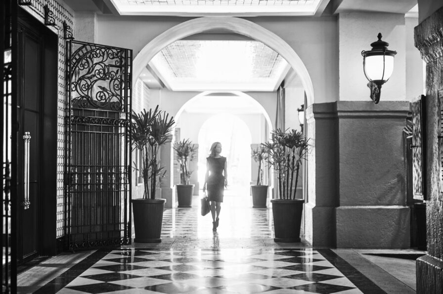 Woman walking through Four Seasons Mexico City lobby with black and white checker tile and grand archway entry, black and white
