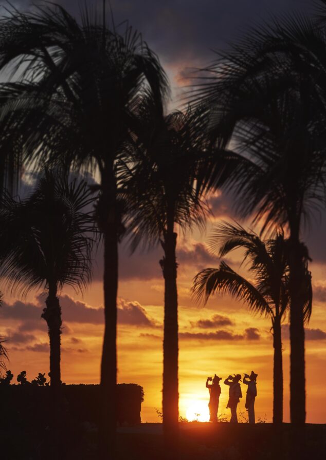 Sunset silhouette of three people performing a huichol ritual in Punta Mita.