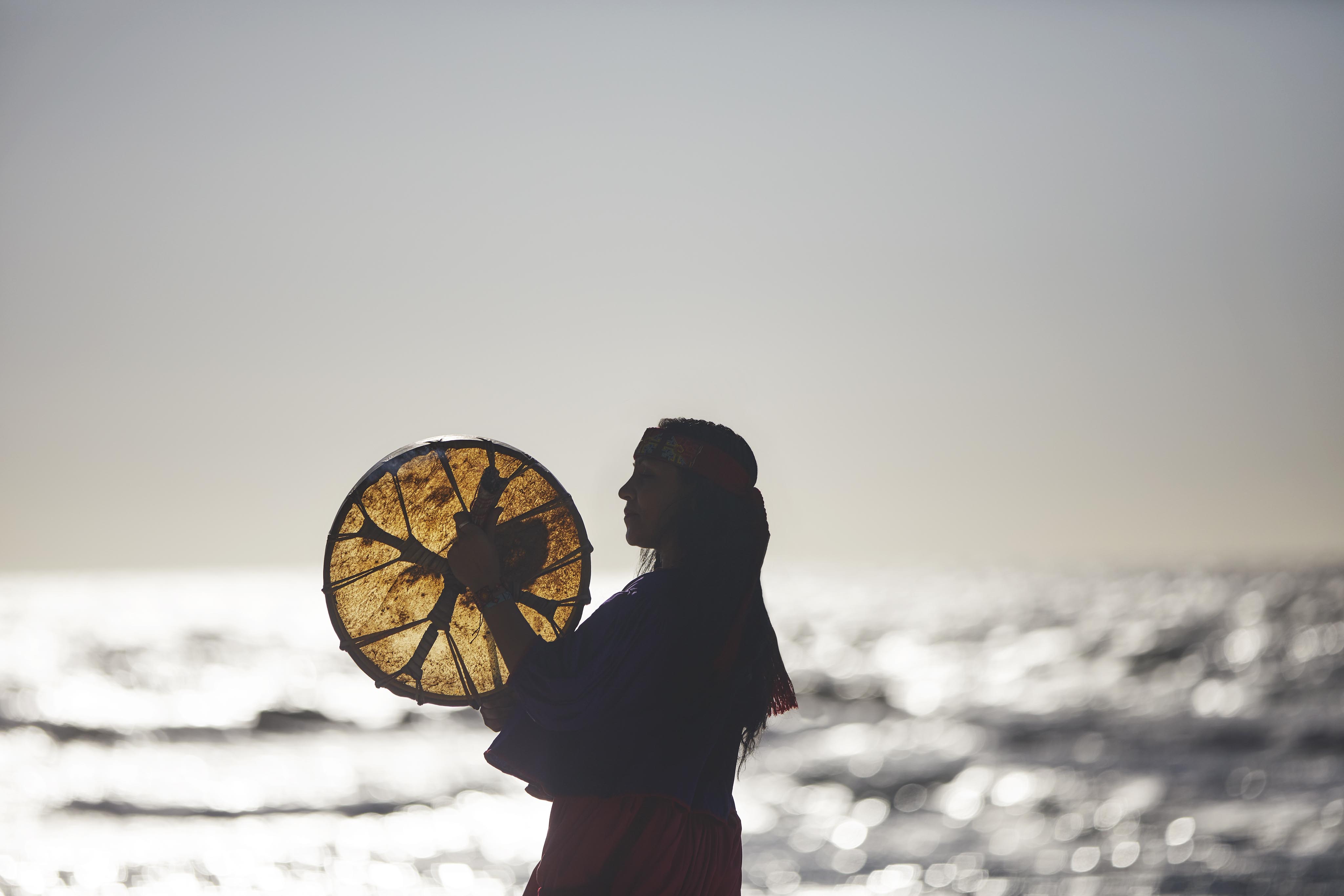 daytime silhouette of women practicing ritual on beach