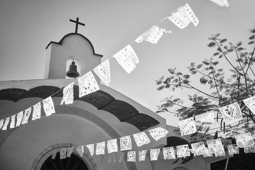 black and white image of la boda flags strung down from top of spanish style church