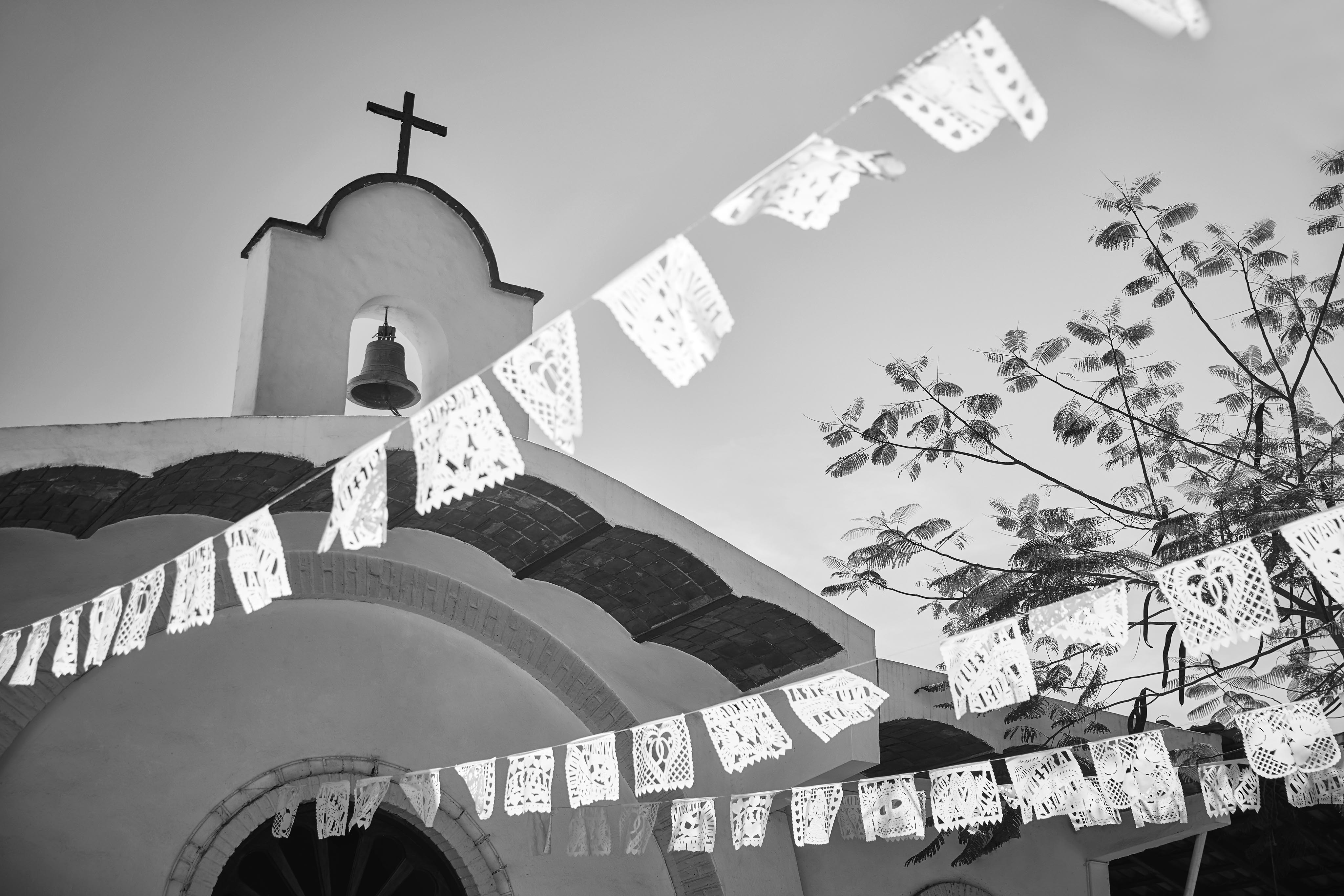 black and white image of la boda flags strung down from top of spanish style church