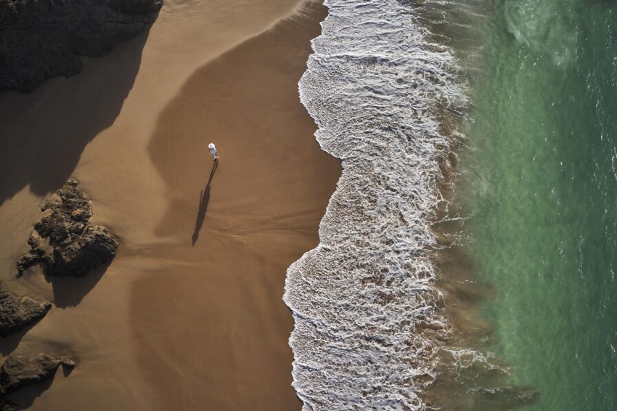 Aerial drone view woman walking secluded dark sand Tamarindo Mexico beach