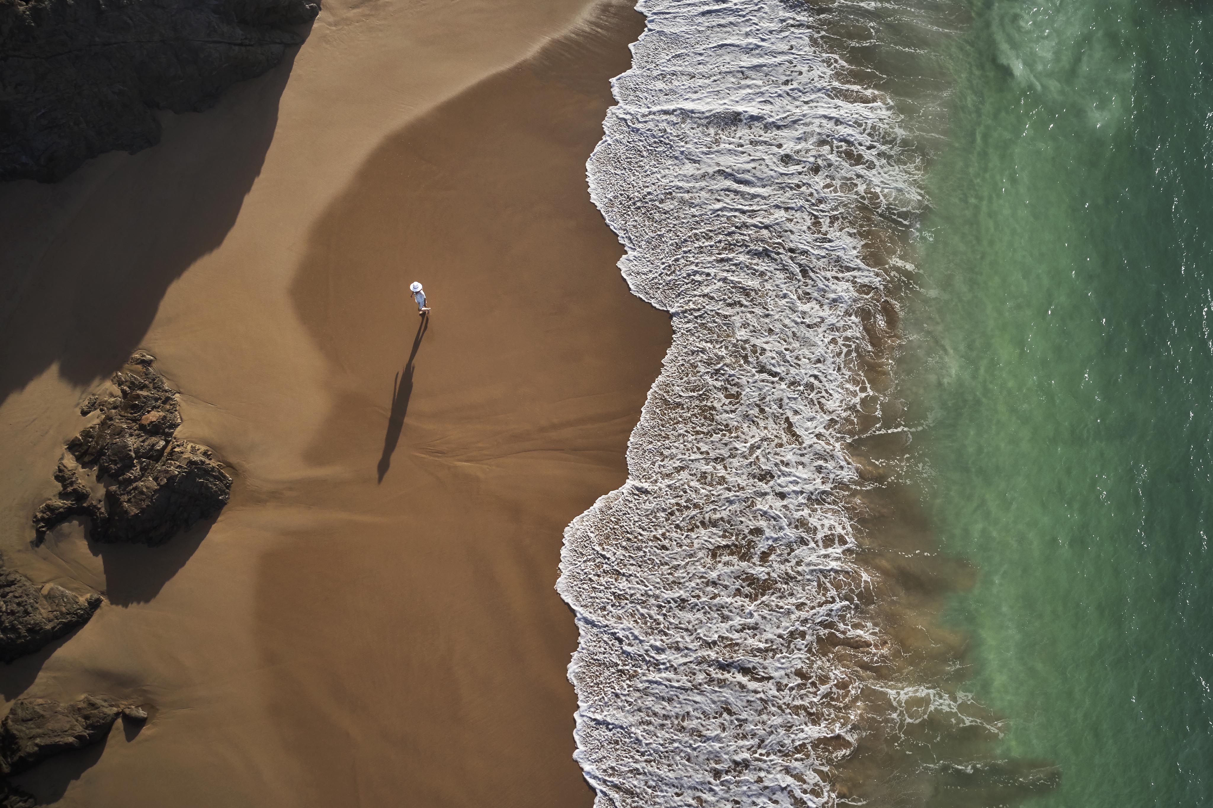 Aerial drone view woman walking secluded dark sand Tamarindo Mexico beach