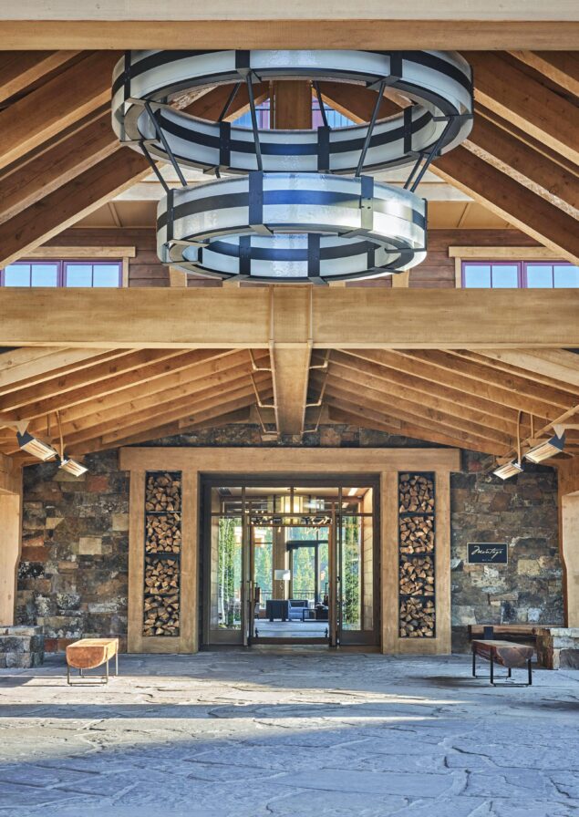 Montage hotel resort Big Sky lobby entrance exterior with wood vaulted roof and modern stone walls; doors open revealing the hotel interior.