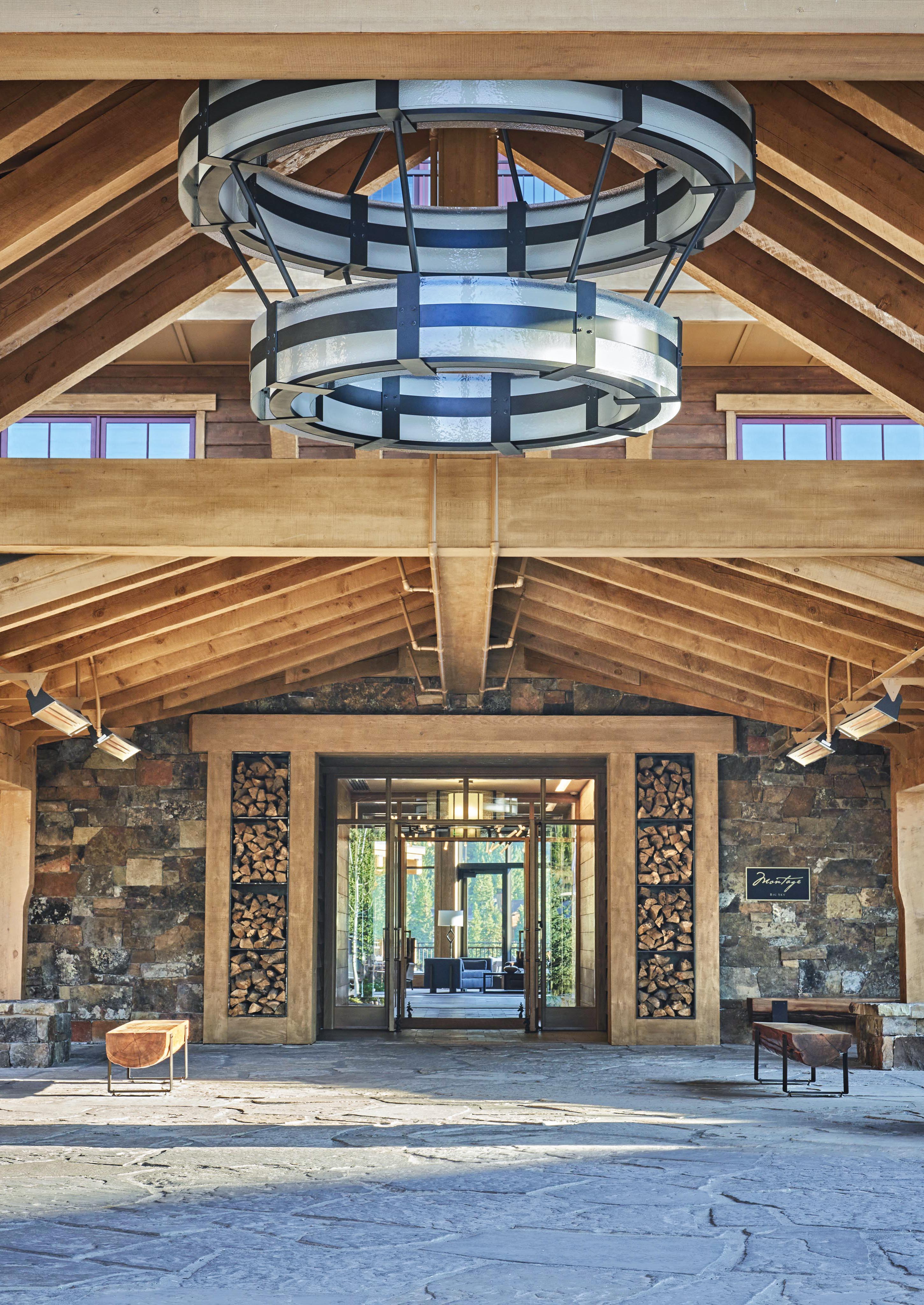 Montage hotel resort Big Sky lobby entrance exterior with wood vaulted roof and modern stone walls; doors open revealing the hotel interior.