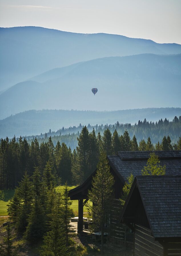 Montana summer landscape tree line mountains with small hot air balloon in distance