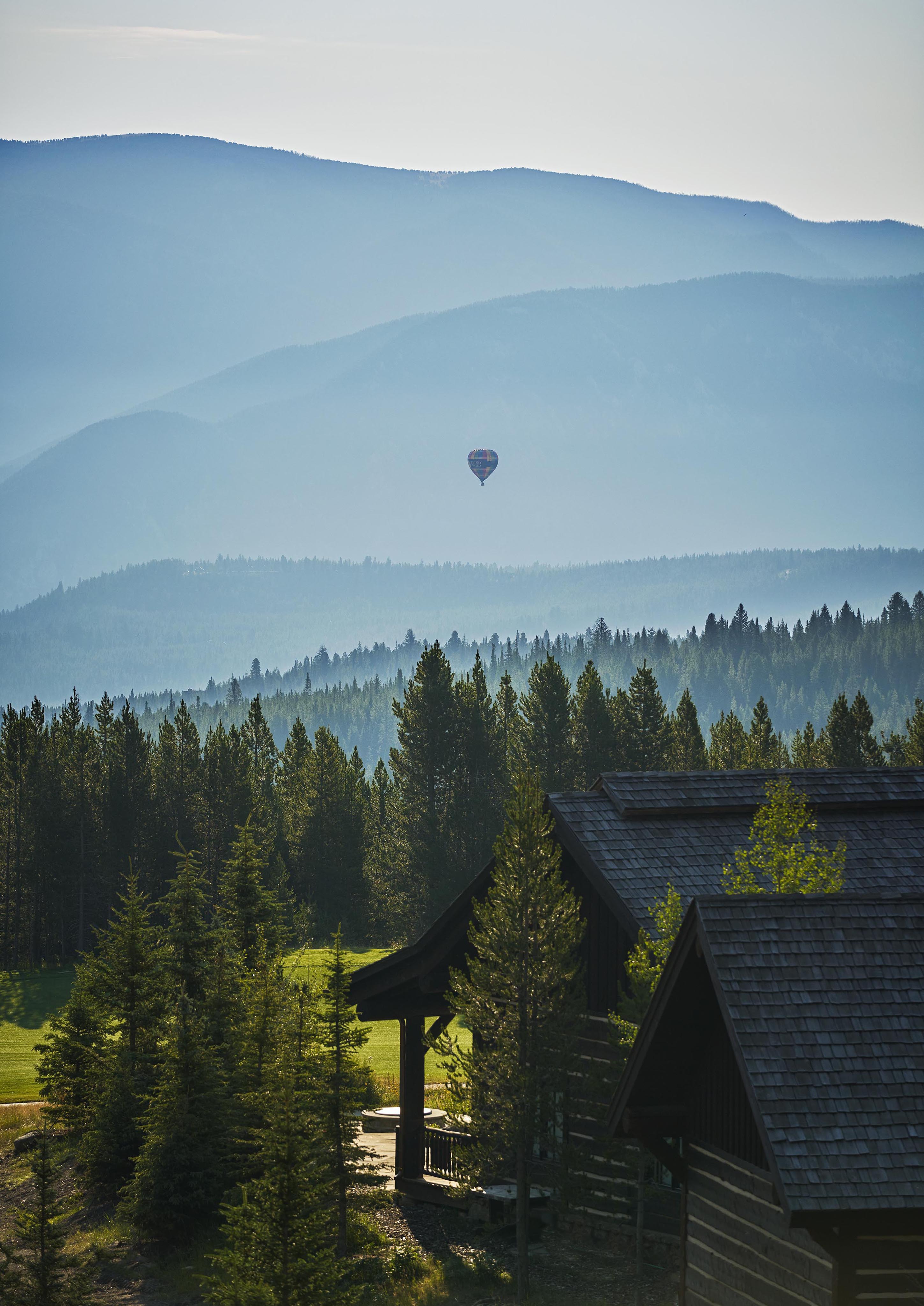 Montana summer landscape tree line mountains with small hot air balloon in distance