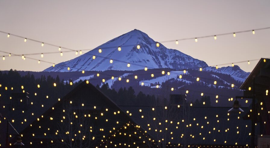 Local town, snow capped mountain string lights Big Sky Montana