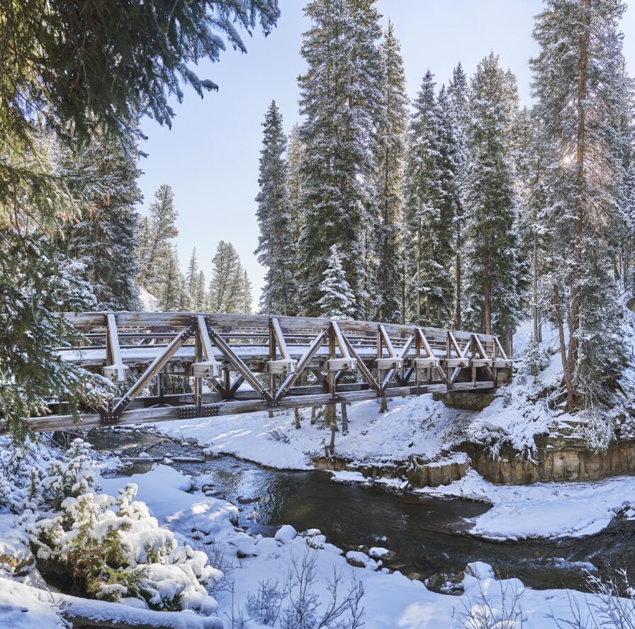 snow covered river bridge crossing hiking area Big Sky