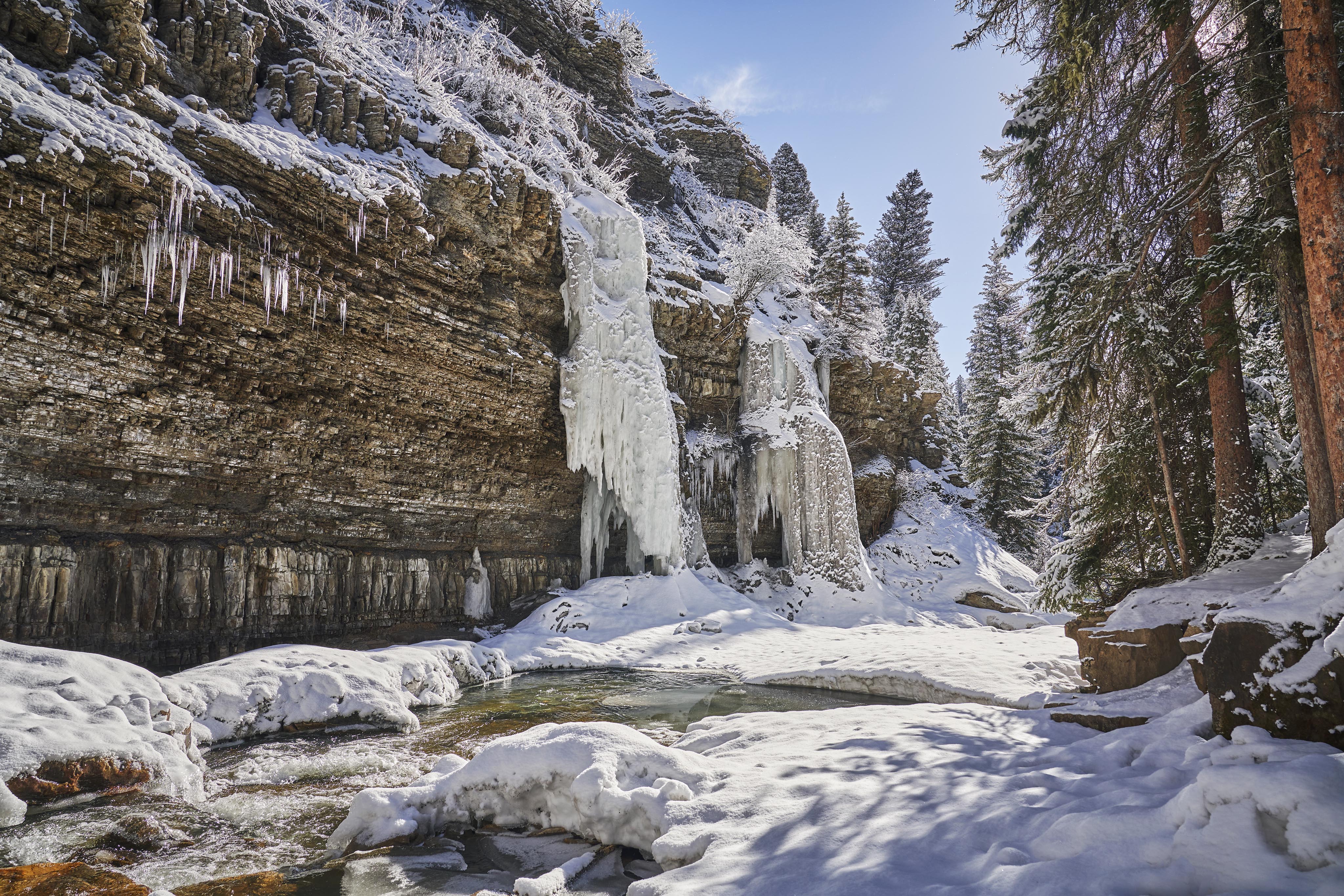 Large Montana rock face, snow covered gallatin river frozen waterfall