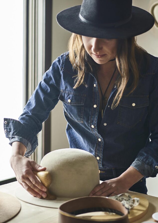 Portrait of woman brushing handmade cowboy hats in Big Sky Montana downtown.
