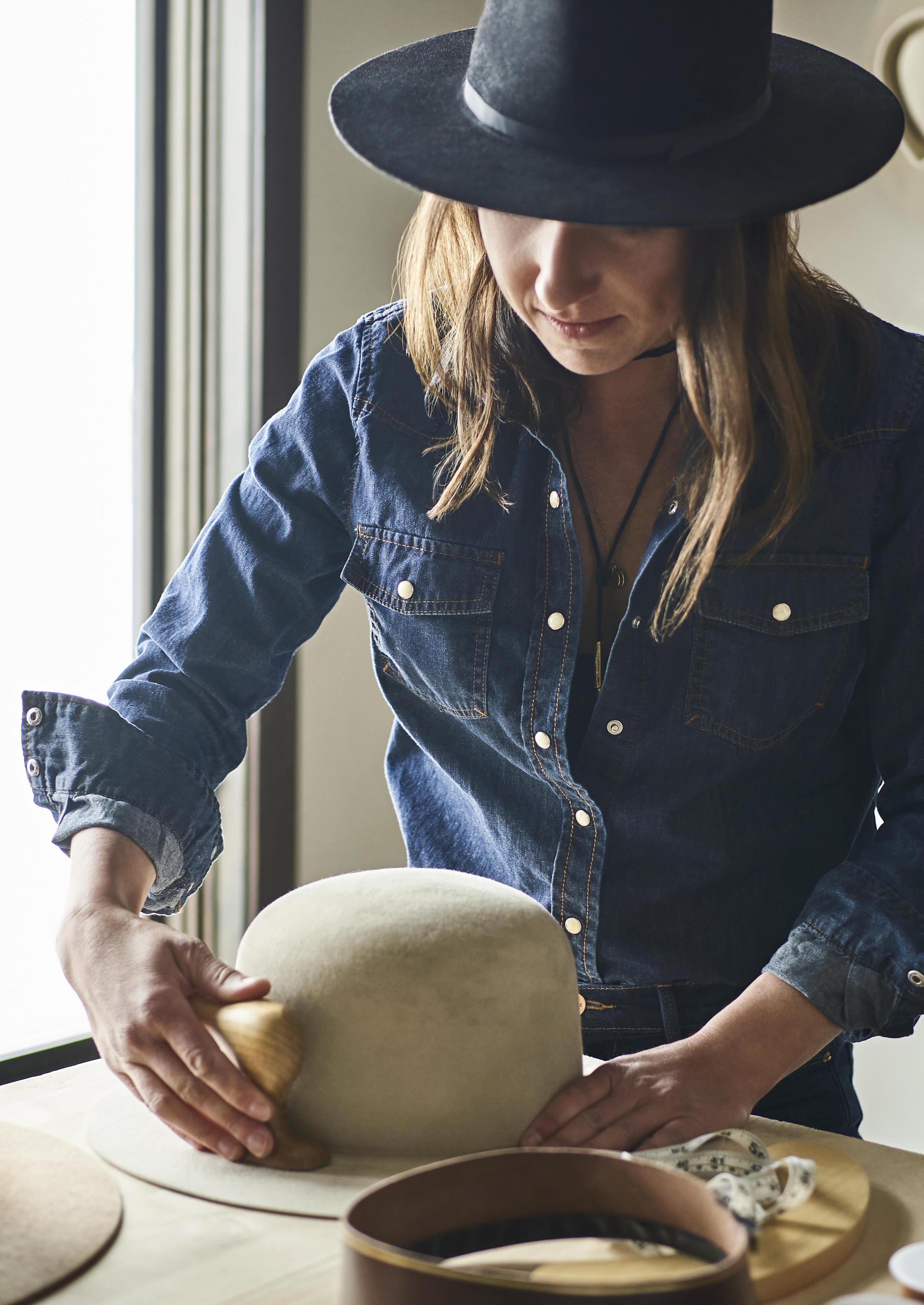 Portrait of woman brushing handmade cowboy hats in Big Sky Montana downtown.