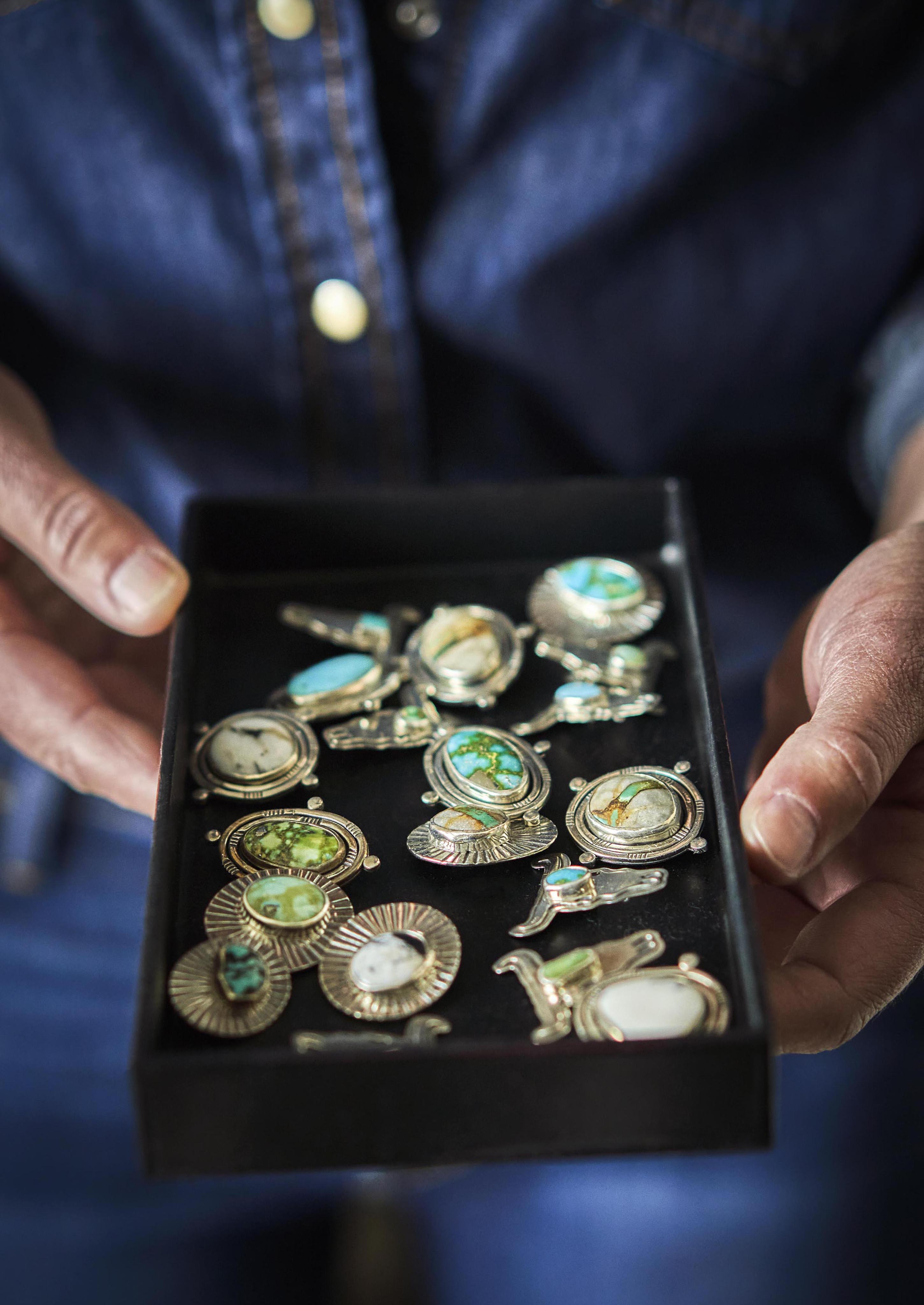 Close up view of woman's hands holding black velvet rectangle case of assorted handmade silver and turquoise jewelry, locally made in Montana.