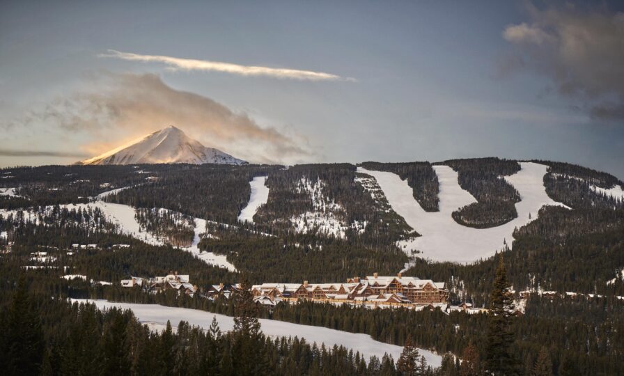Montage Big Sky luxury hotel mountainside ski resort landscape at dusk with Lone Mountain in the distance.