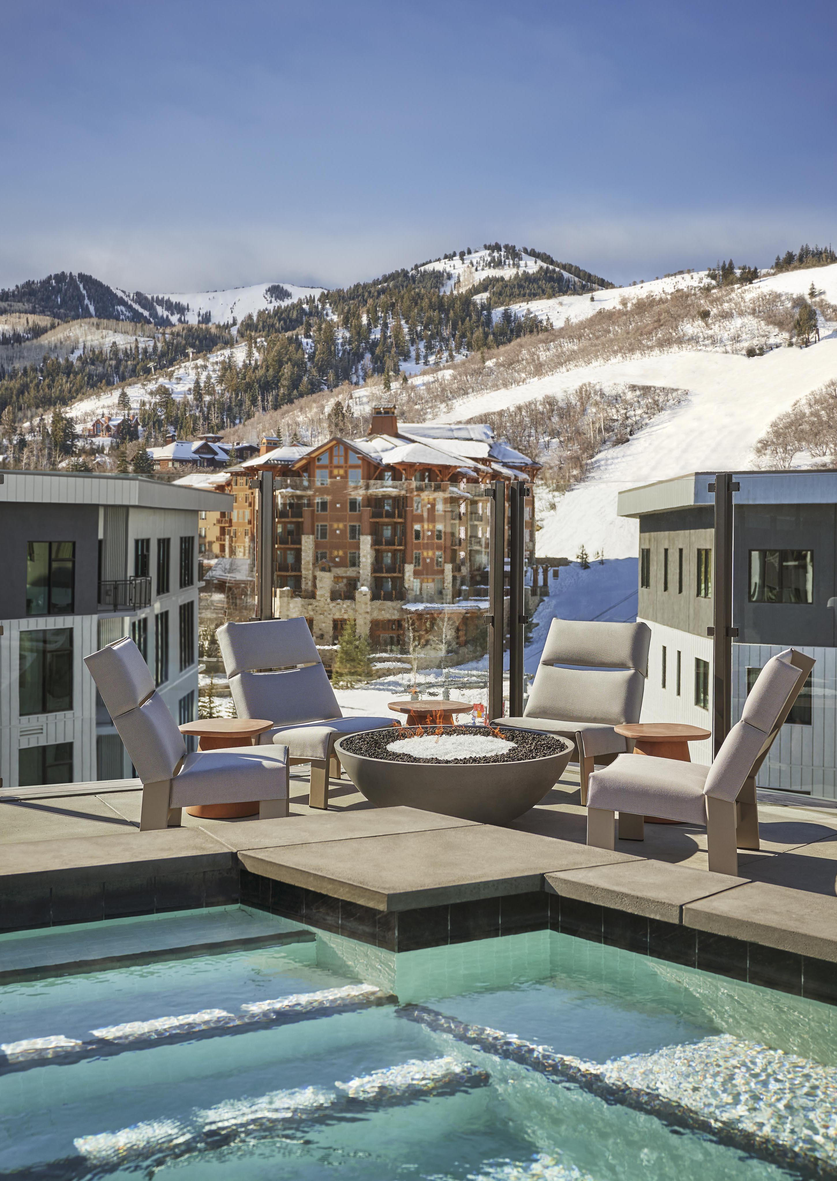Luxury resort pool with adjacent ski chalets and snow covered Park City Utah mountains in the background.