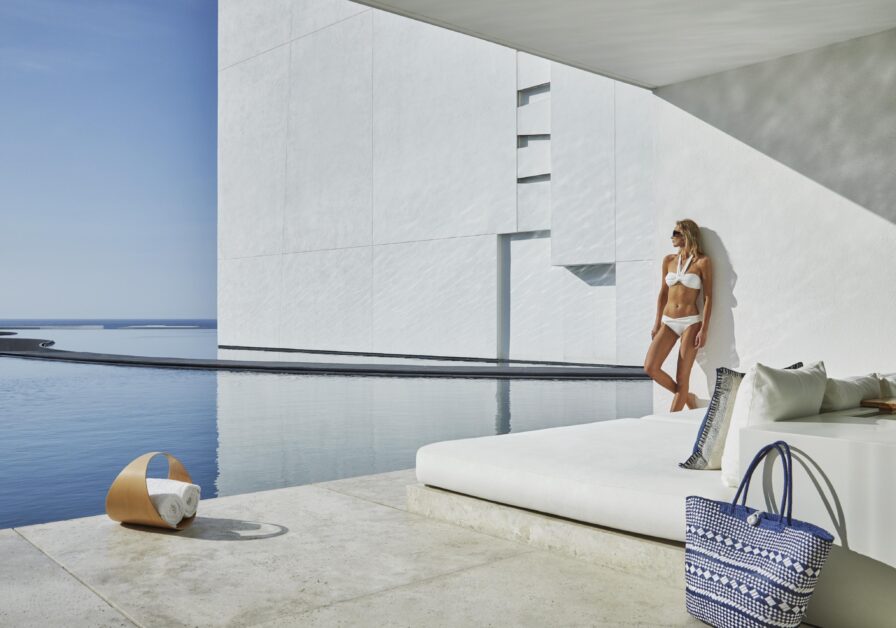 woman leaning against modern furnished open air villa with marble patio and plunge pool in Los Cabos